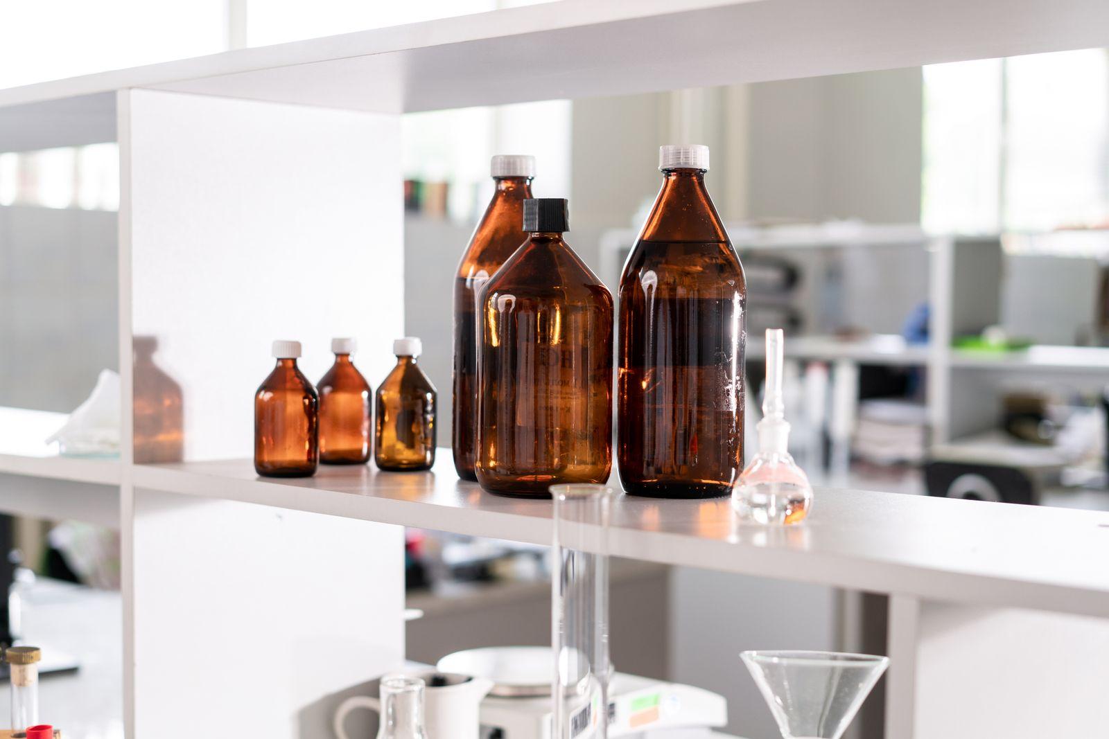Amber glass reagent bottles of several sizes standing on a white laboratory shelf