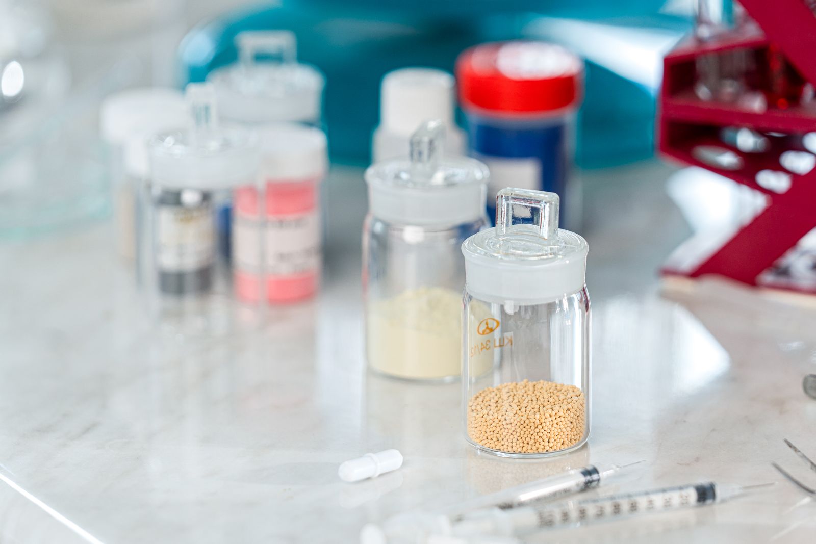Stoppered glass jars of catalyst pellets and powders on a laboratory bench