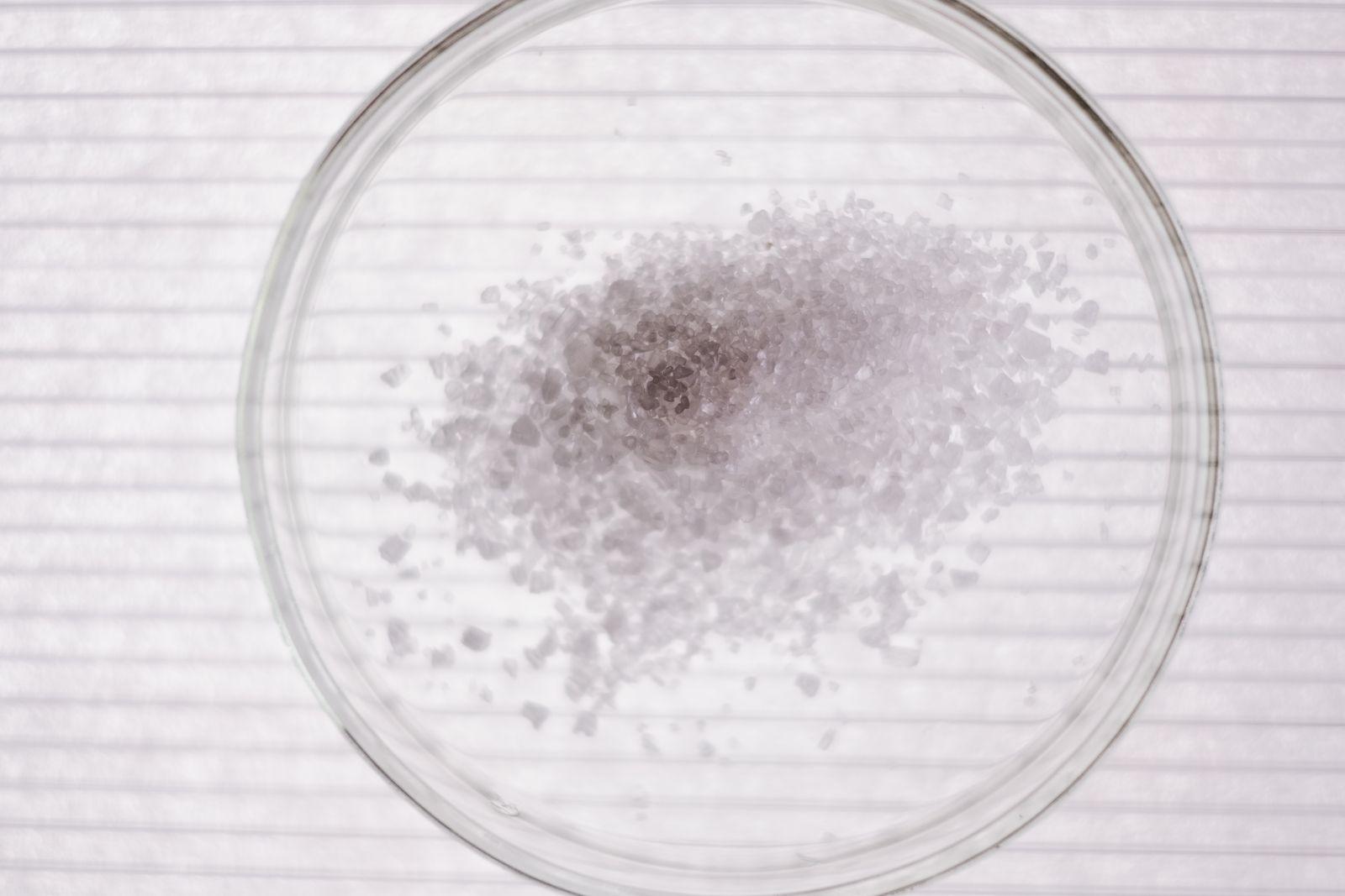 Coarse crystals gathered in a shallow glass dish, seen from directly above