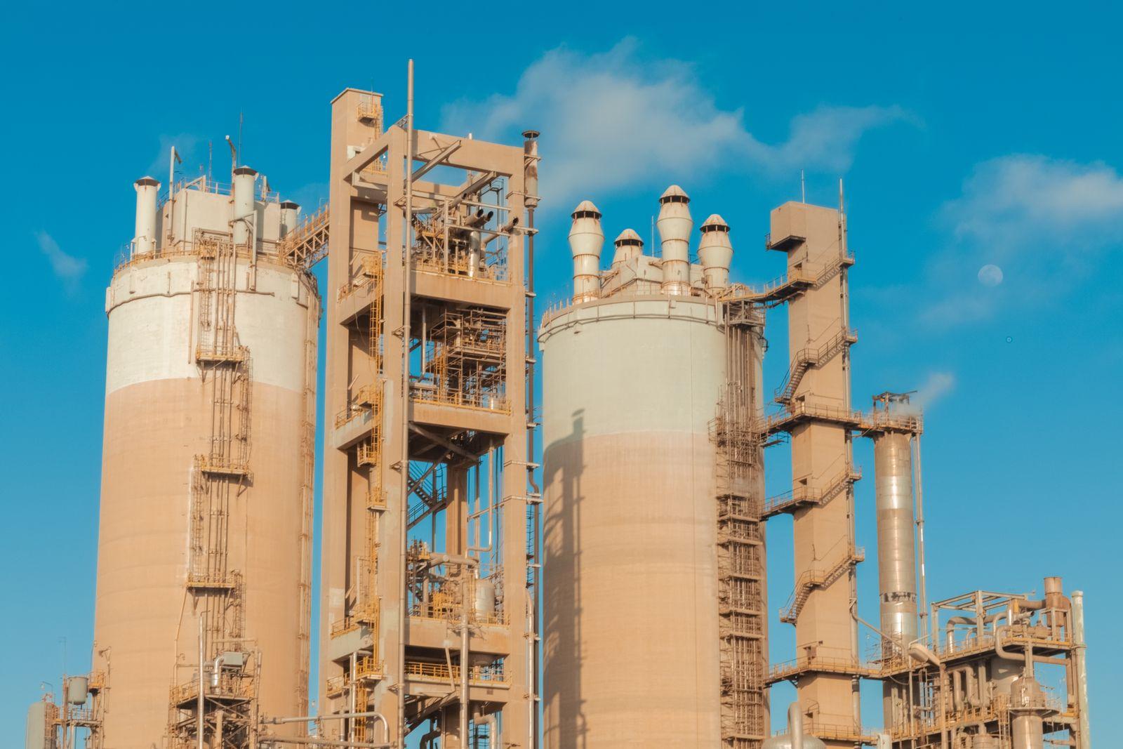 Tall process columns, stair towers and vent stacks at a chemical plant against a clear sky