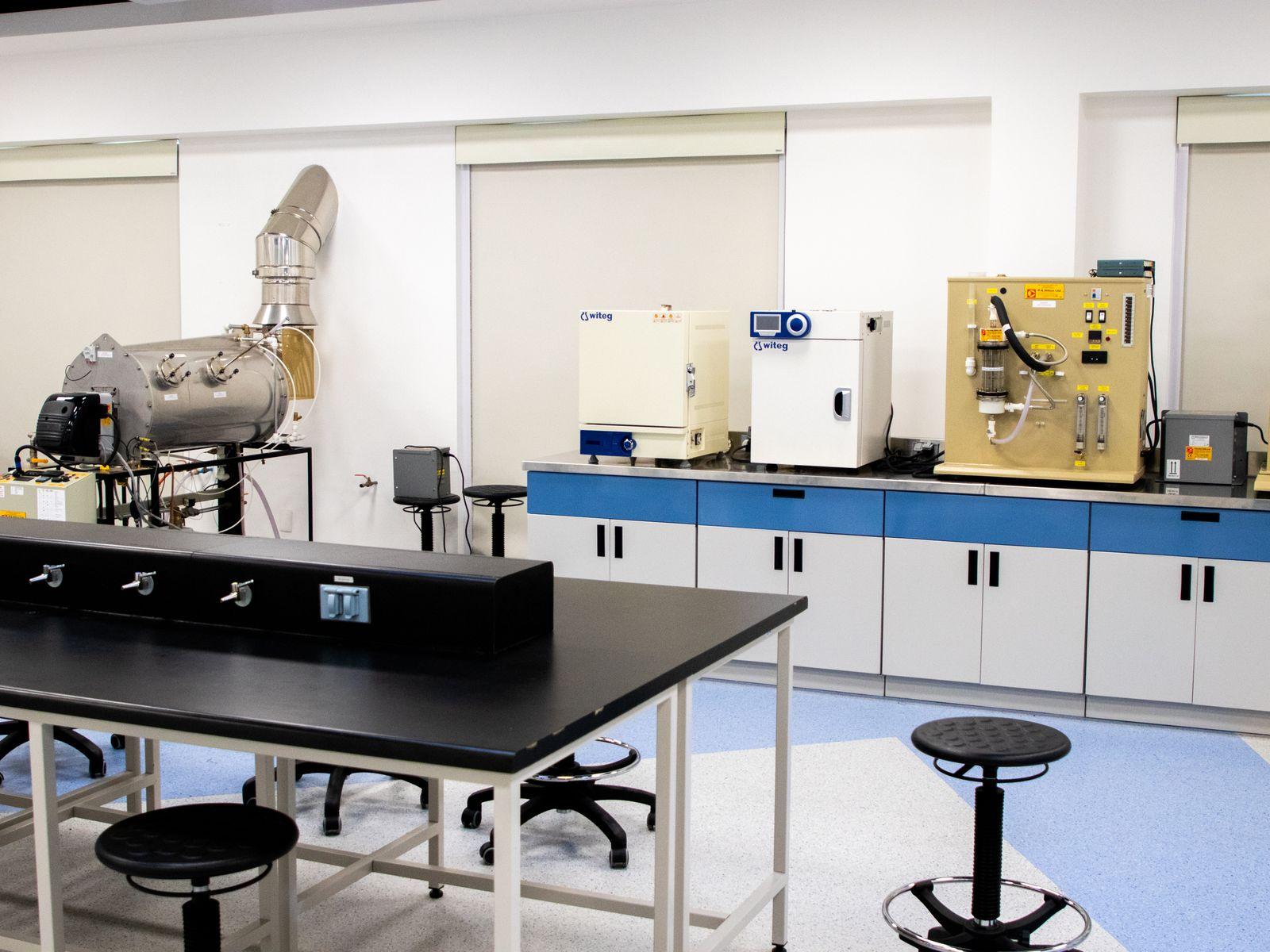 A modern, well-lit chemical laboratory interior with stainless benches and equipment