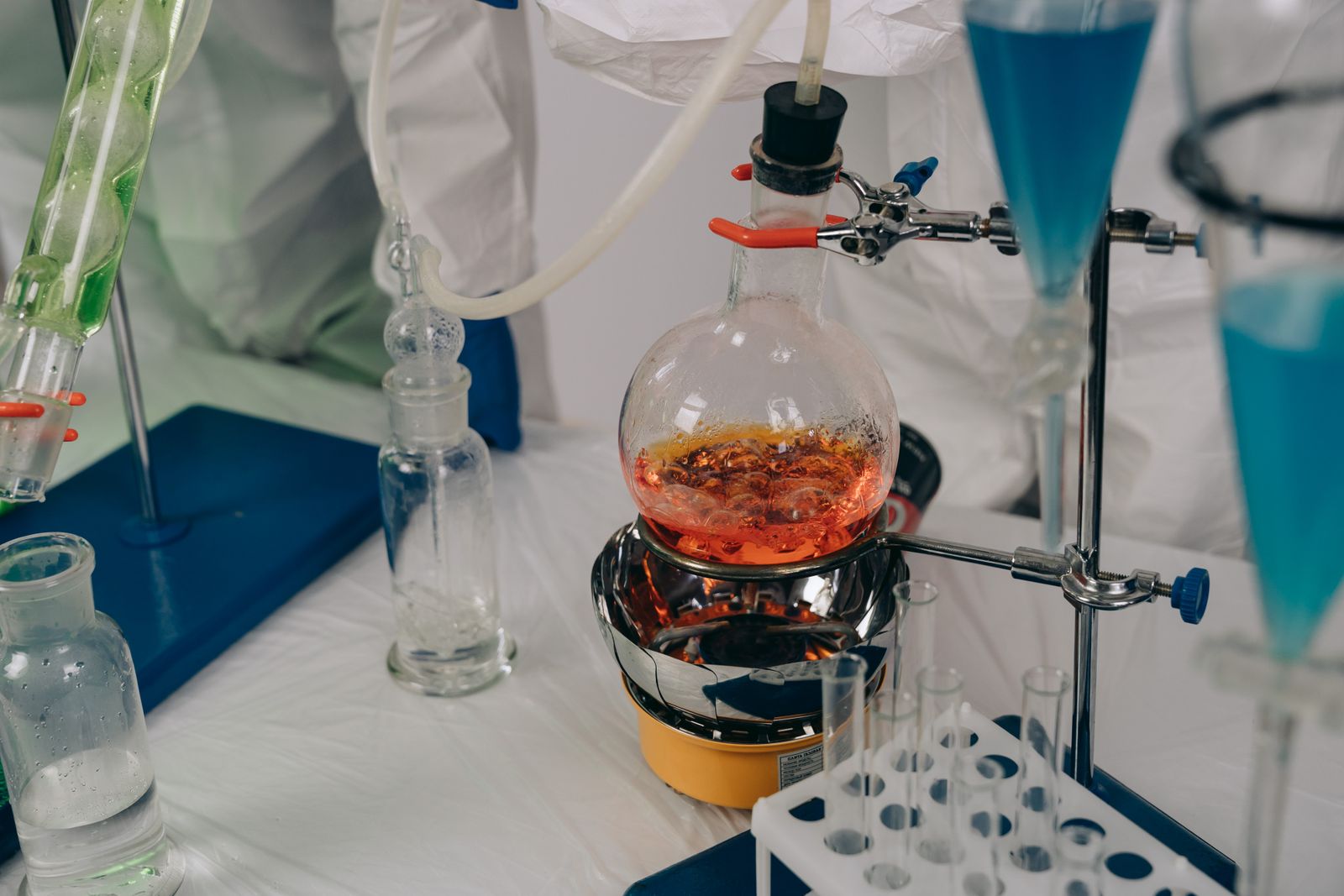 A glass reactor flask under reflux, heated on a mantle with a condenser above