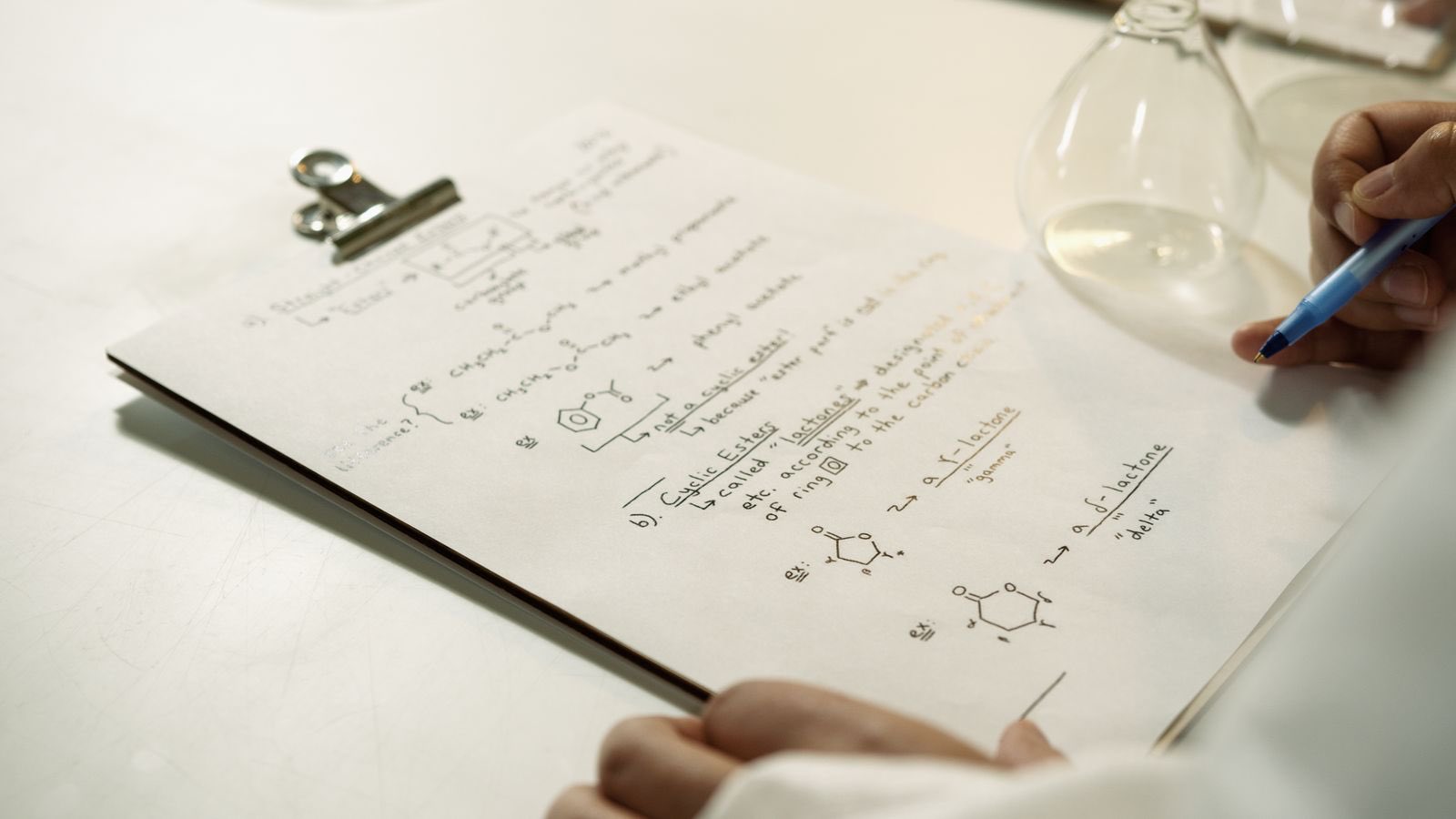 Handwritten route notes and reaction schemes on a laboratory clipboard
