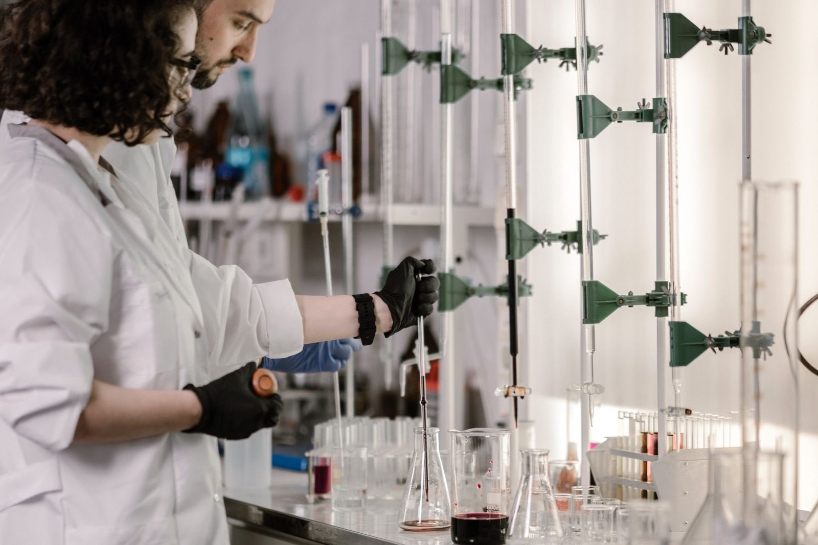 Two chemists working together over glassware at a laboratory bench