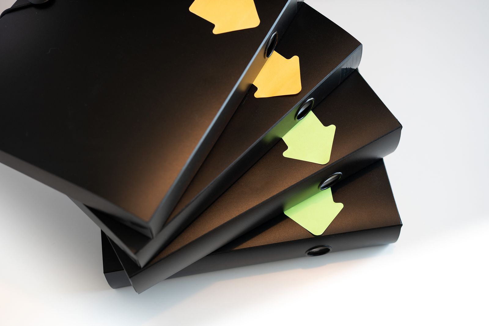 Three black ring binders stacked and fanned out, each marked with a colour-coded index tab