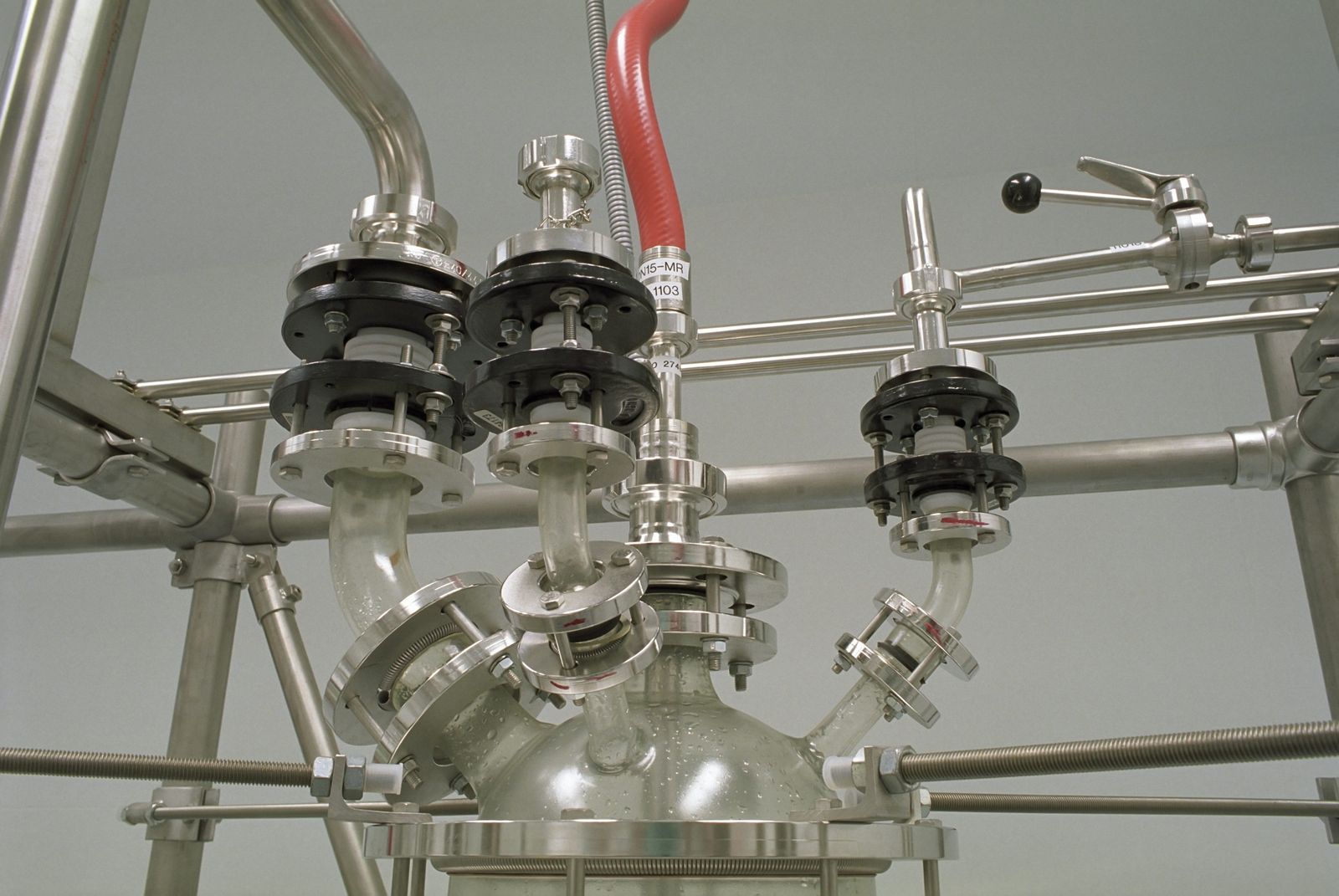 The head of a jacketed glass reactor, with flanged nozzles, clamps and connected pipework above the vessel