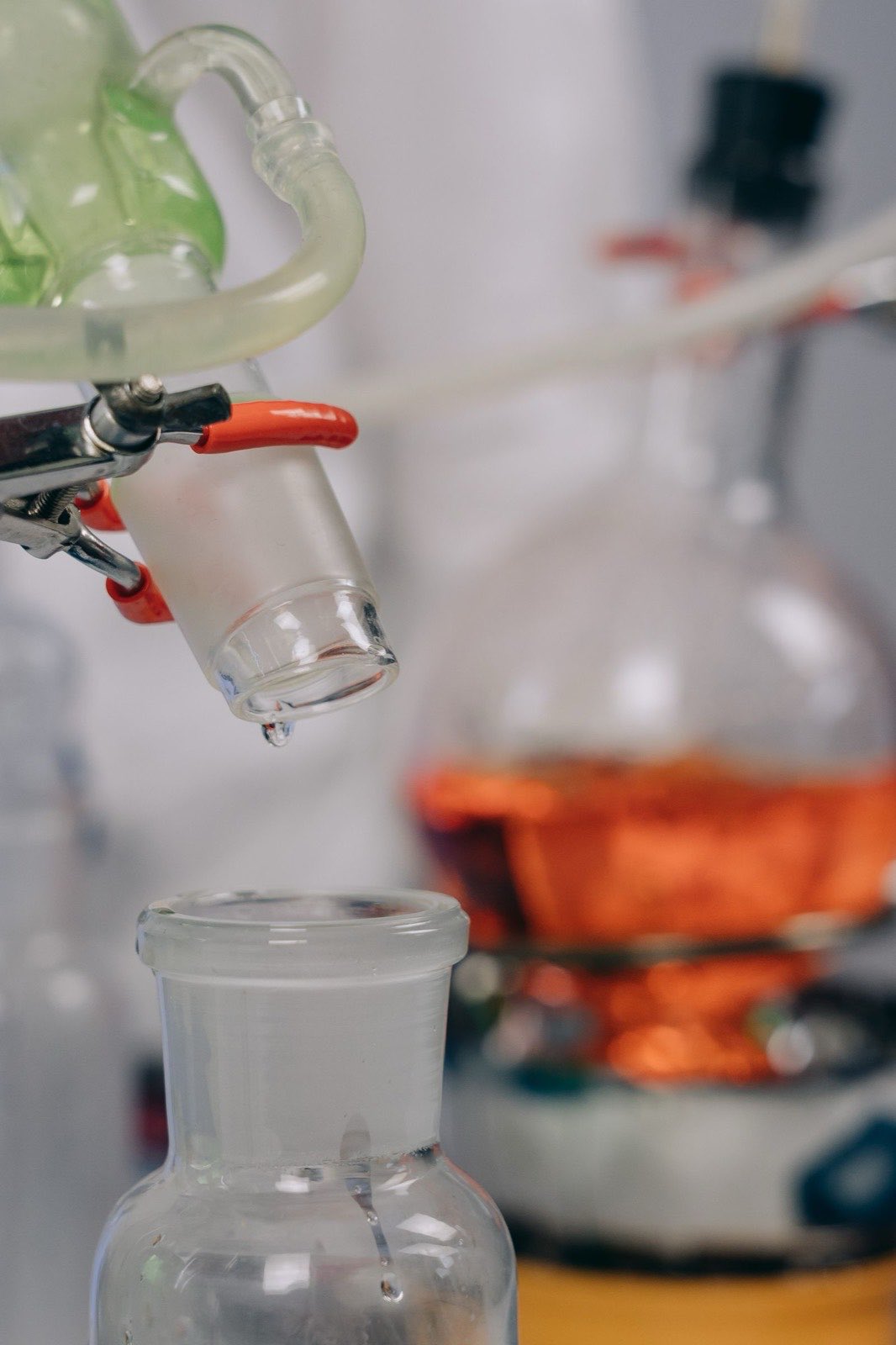 Distillation glassware clamped on a stand, with condensate collecting below